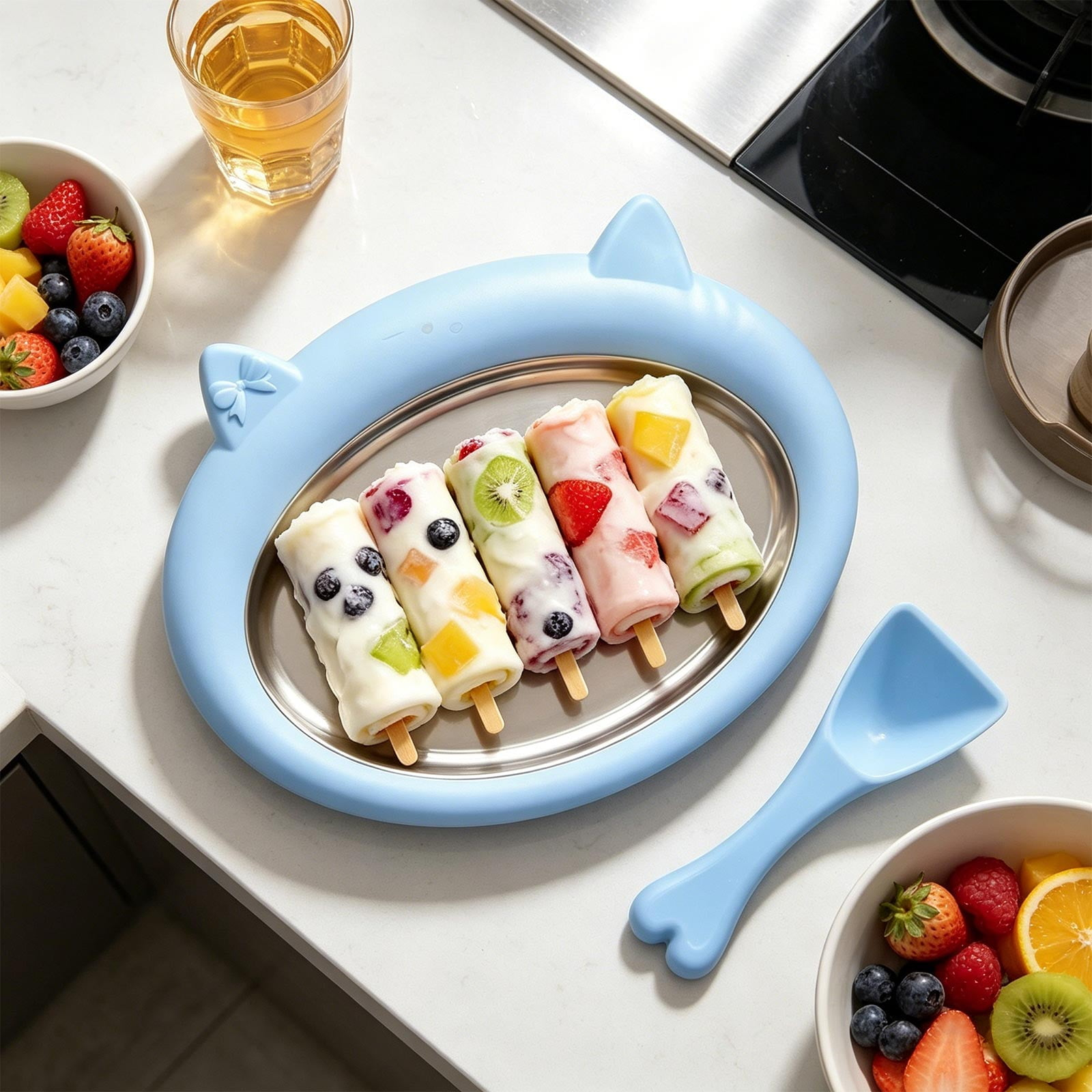 Eisrollen mit Früchten auf blauem Teller, daneben Obstschale und Löffel.