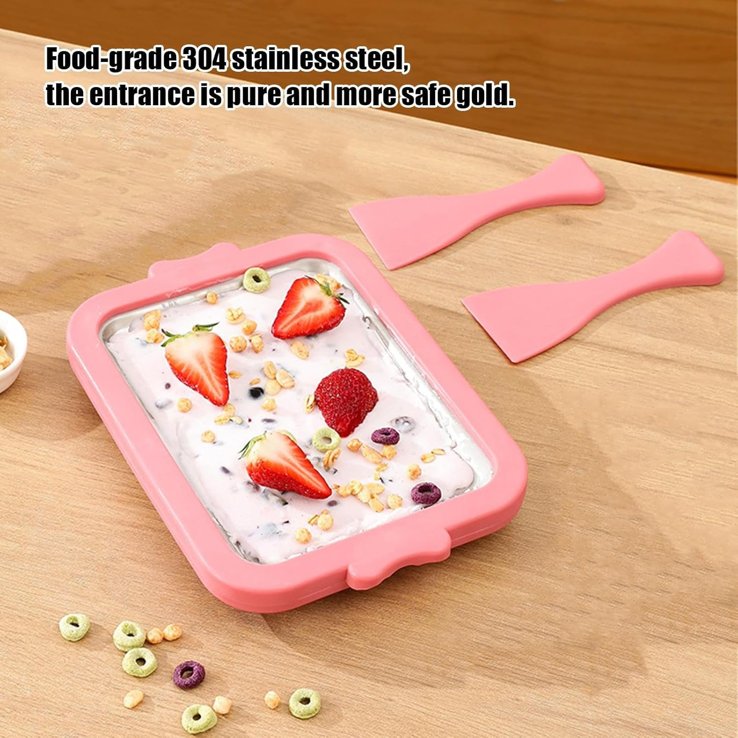 Ein rosa Eisbereiter mit Erdbeeren, Cerealien und Löffeln auf einem Holztisch.