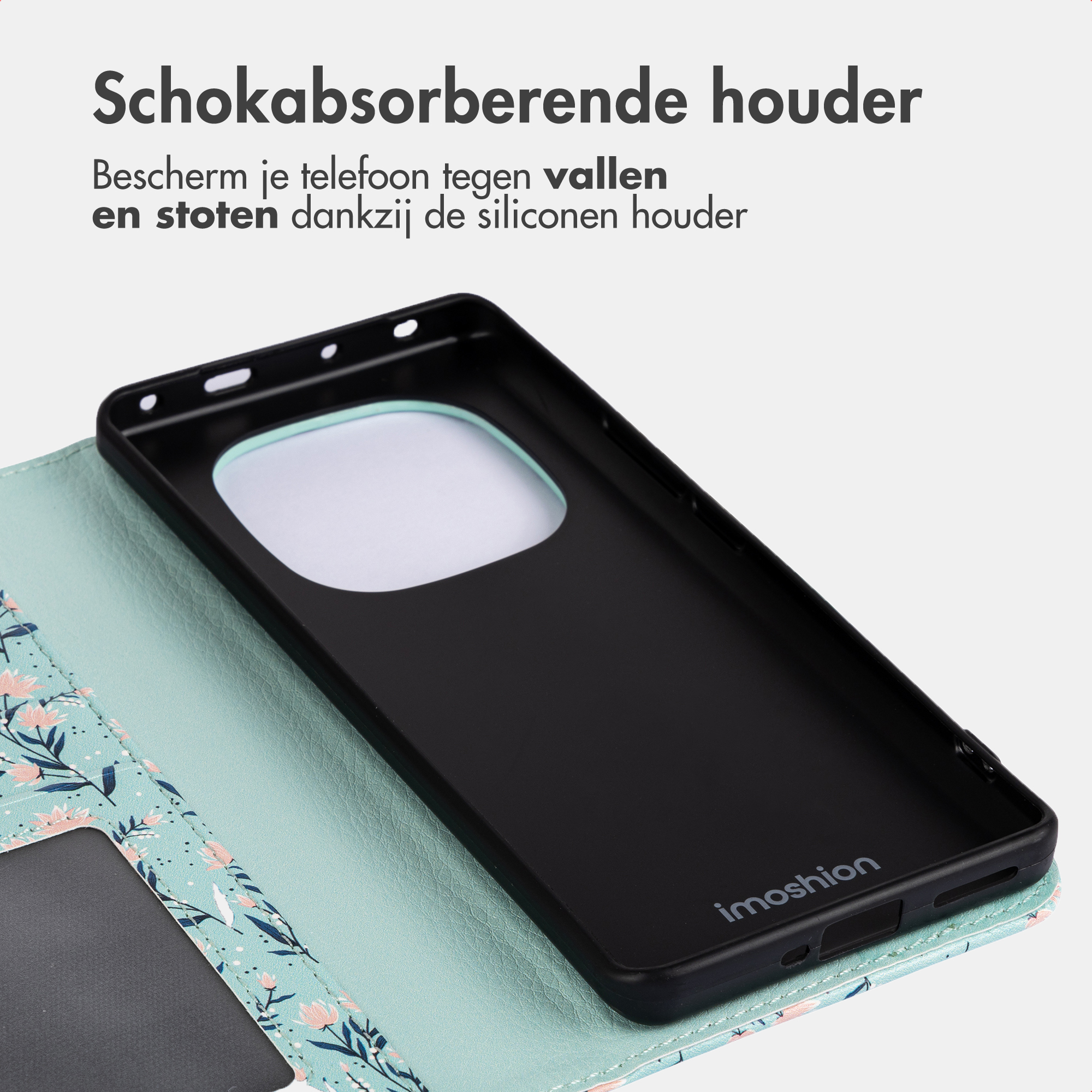 Un supporto per telefono in silicone nero giace su una custodia a portafoglio floreale azzurra, con testo sopra su sfondo grigio.