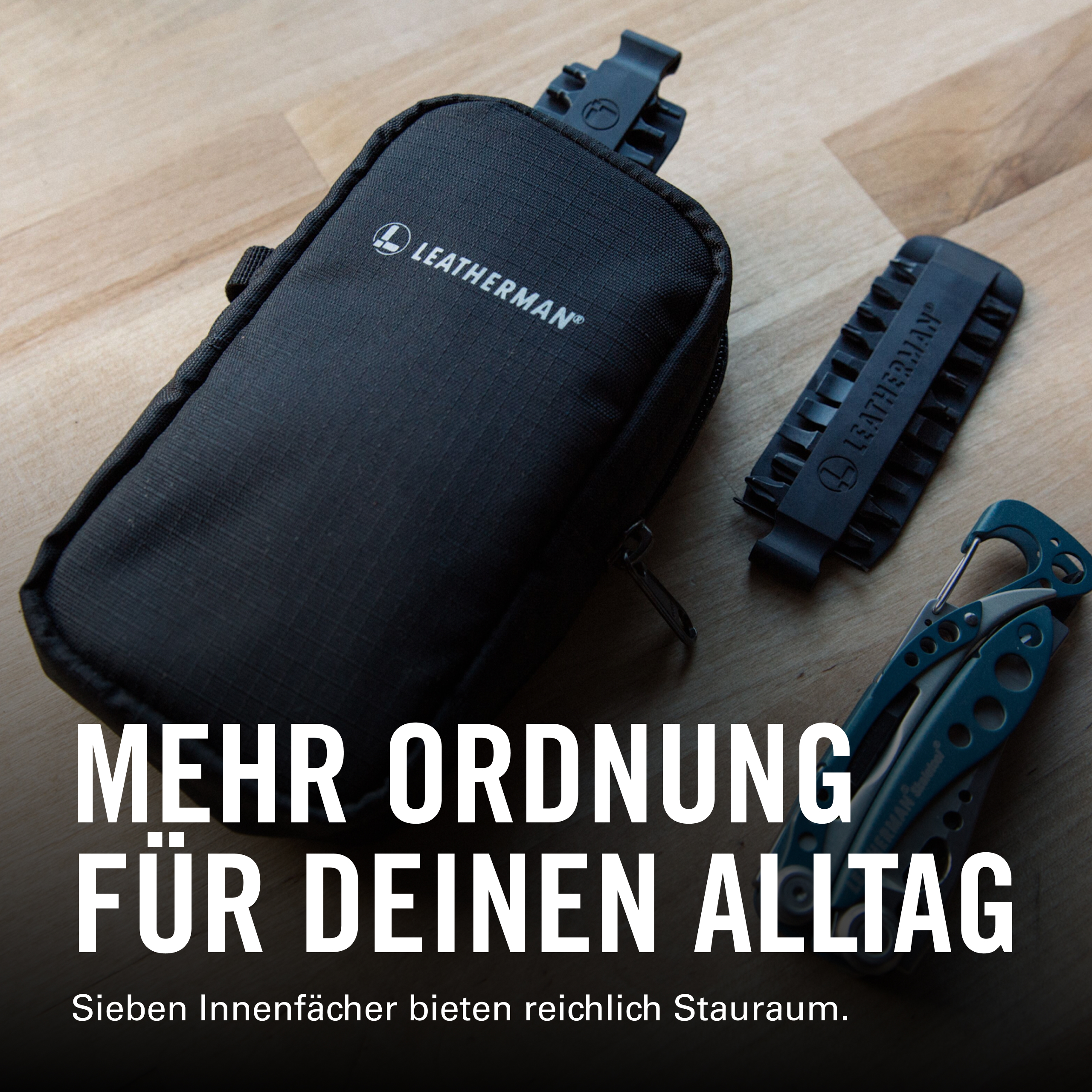 Schwarze Leatherman-Tasche, Bit-Halter und Multitool auf Holzboden.