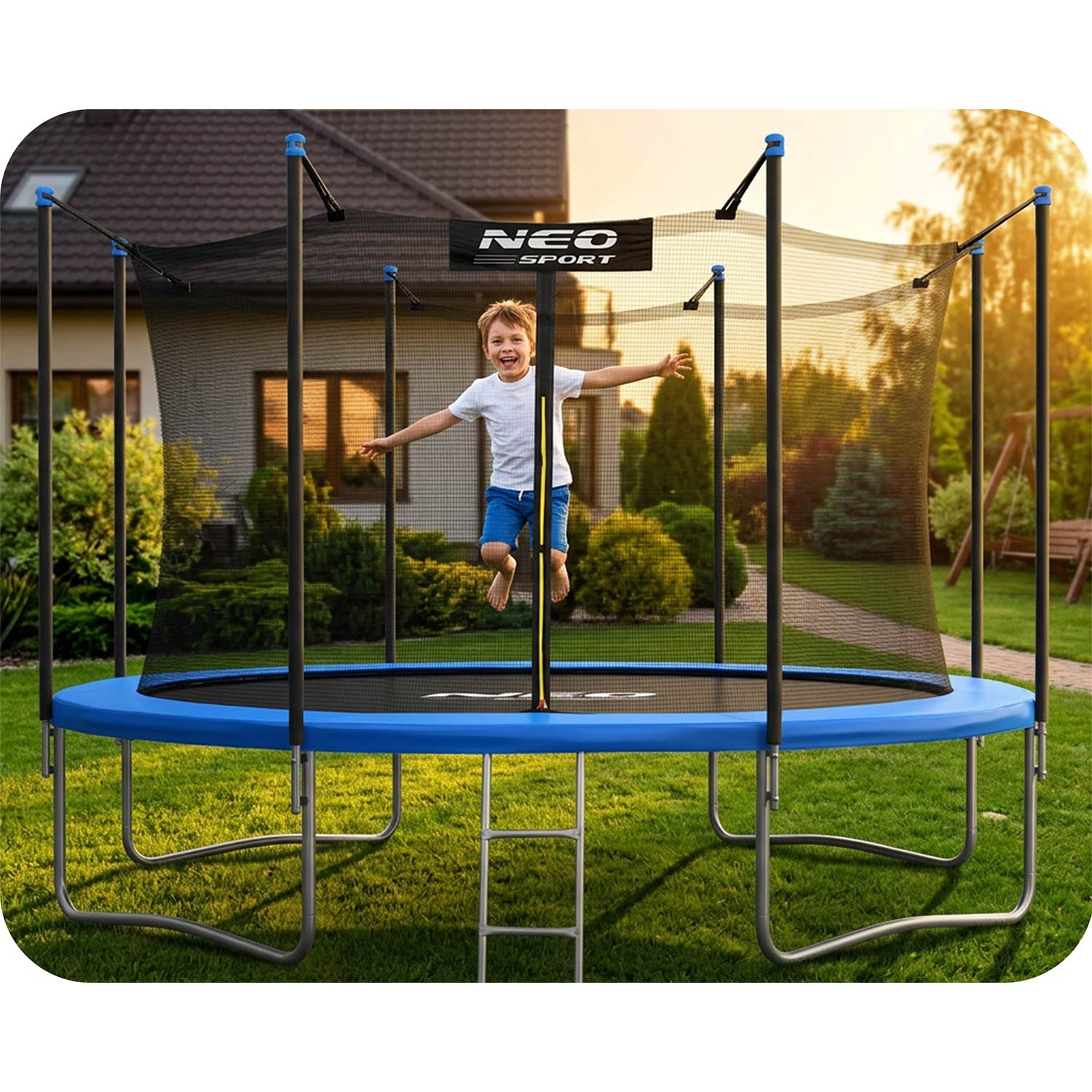 Chłopiec skacze na niebieskiej trampolinie w ogrodzie z domem w tle.