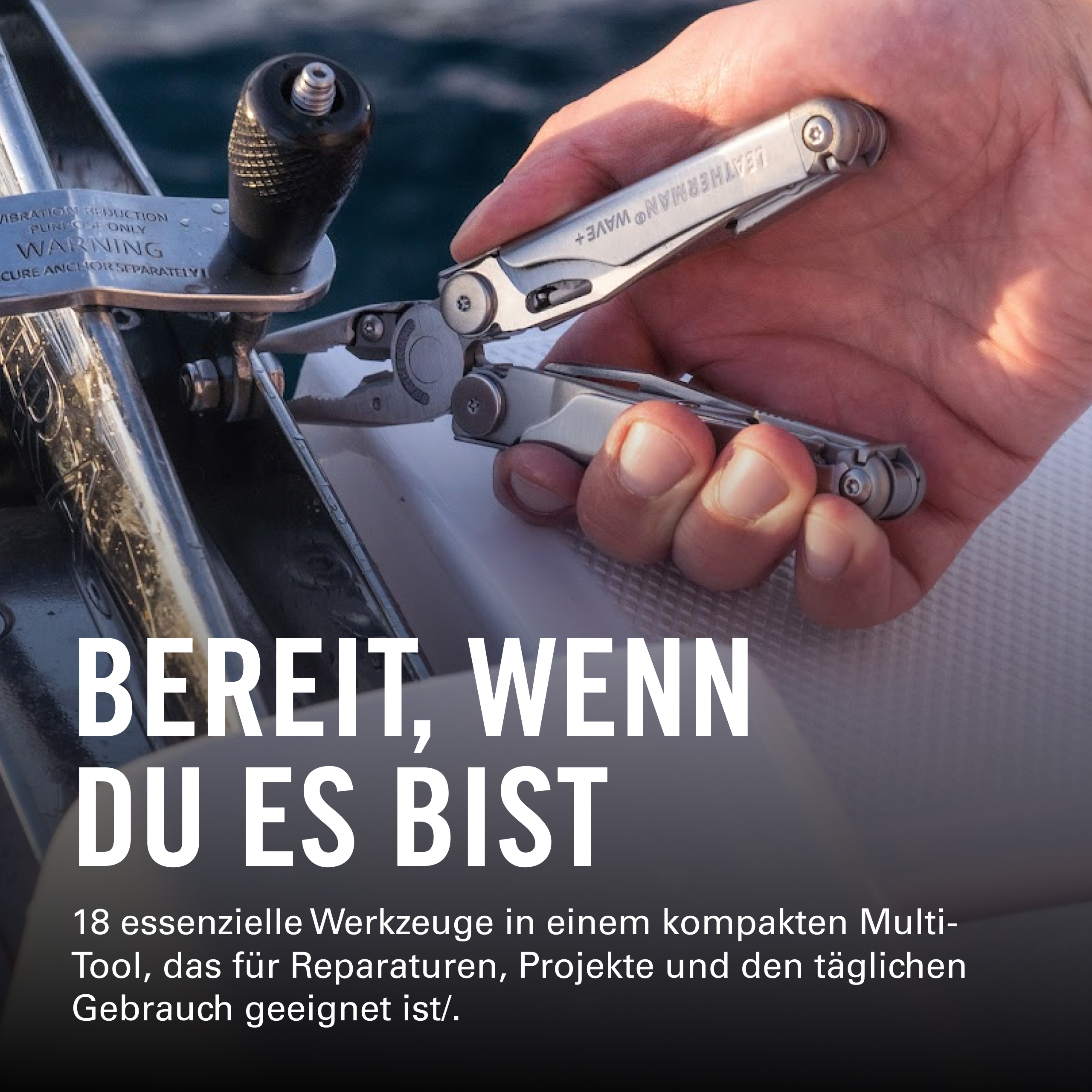 Eine Hand hält ein silbernes Multitool mit Zange vor einem Anker auf dem Wasser.