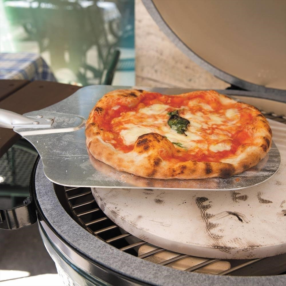 Bir Margherita pizza, pizza küreğiyle bir mangaldan kaldırılıyor.
