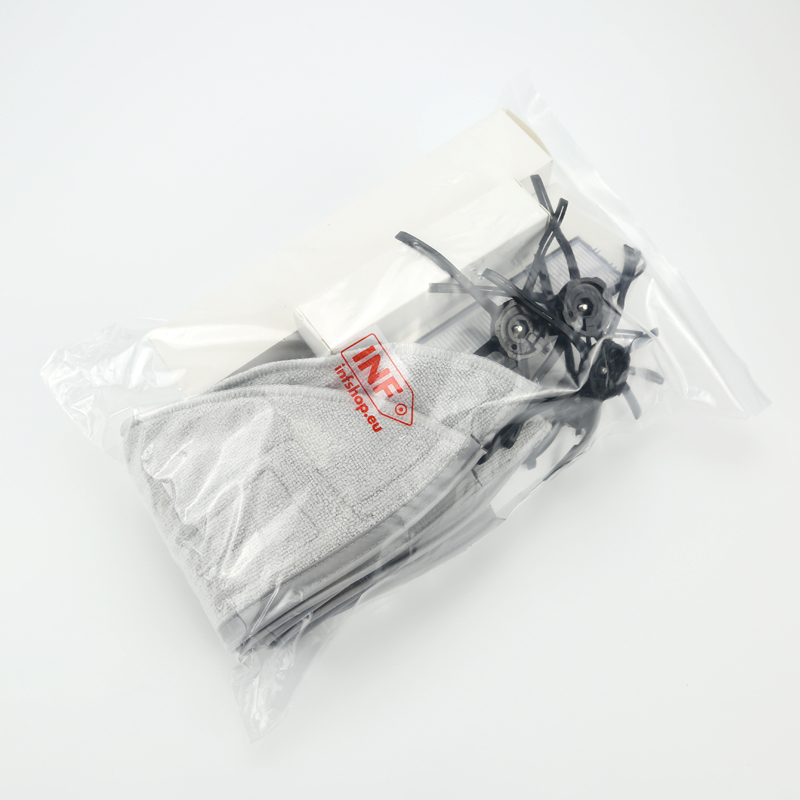 Eine durchsichtige Plastiktüte enthält ein graues Mikrofasertuch, weiße Filter und schwarze Bürstenaufsätze für einen Saugroboter.