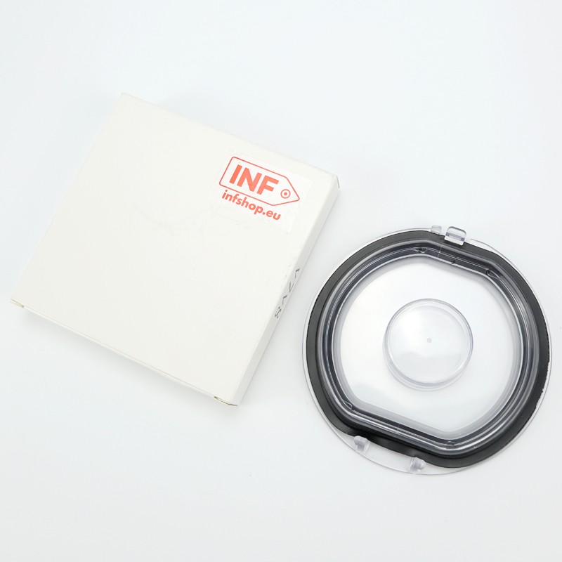 A white box and a clear round cover with a black gasket sit on a white surface.