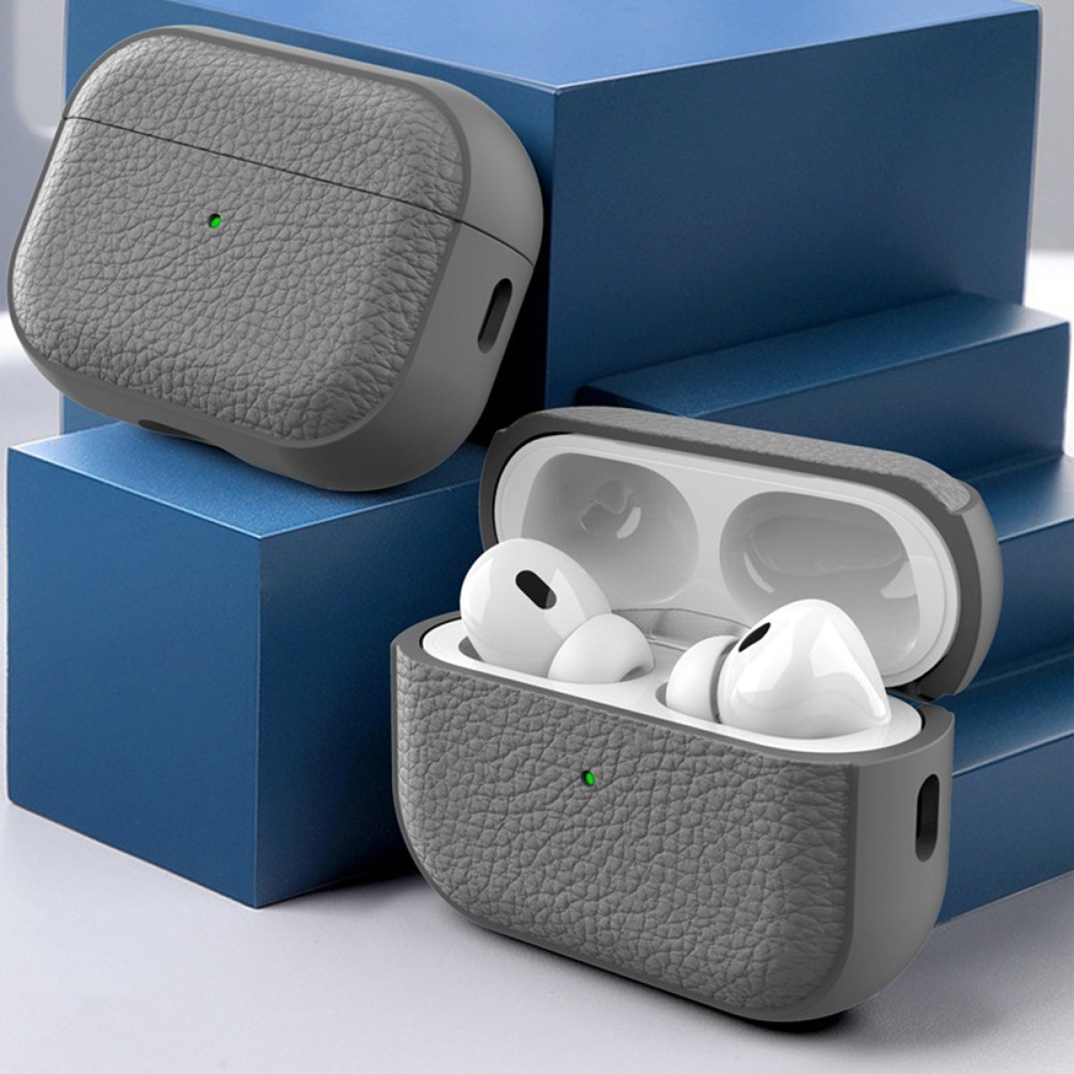 Custodia AirPod in pelle grigia con auricolari aperti e luce verde.