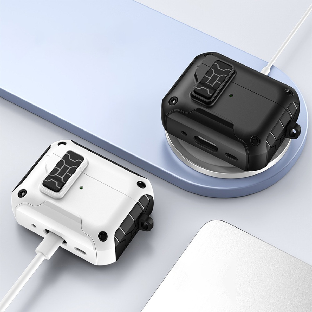 Due robuste custodie per auricolari, una bianca e una nera, sono mostrate; quella nera è su un caricabatterie wireless, quella bianca si ricarica tramite USB.