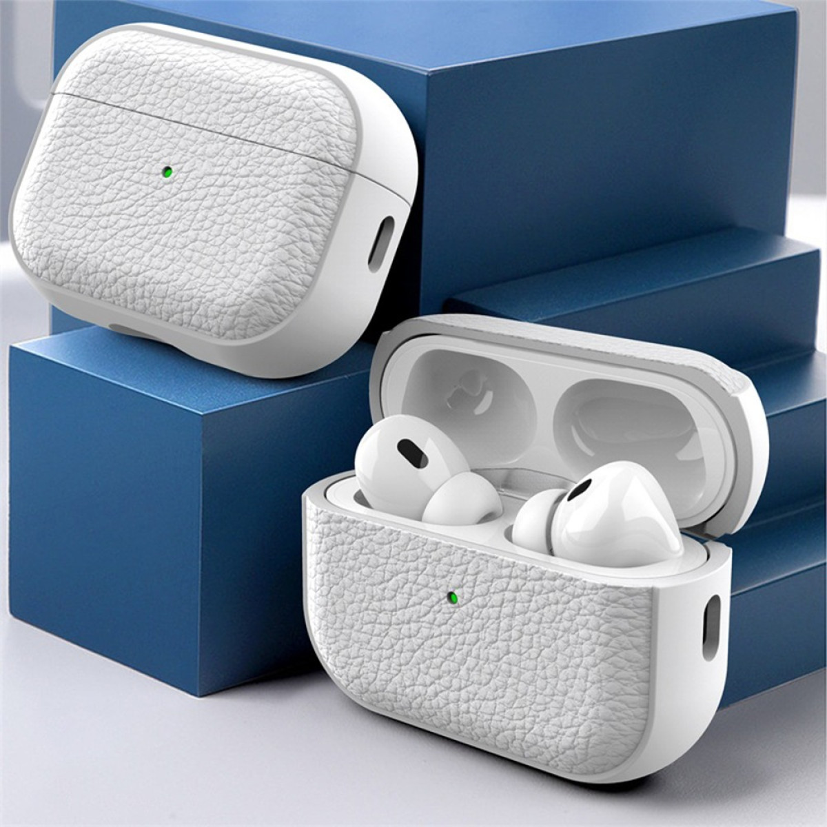 Dos estuches blancos texturizados para auriculares sobre bloques azules. Uno cerrado, el otro abierto con auriculares blancos dentro.