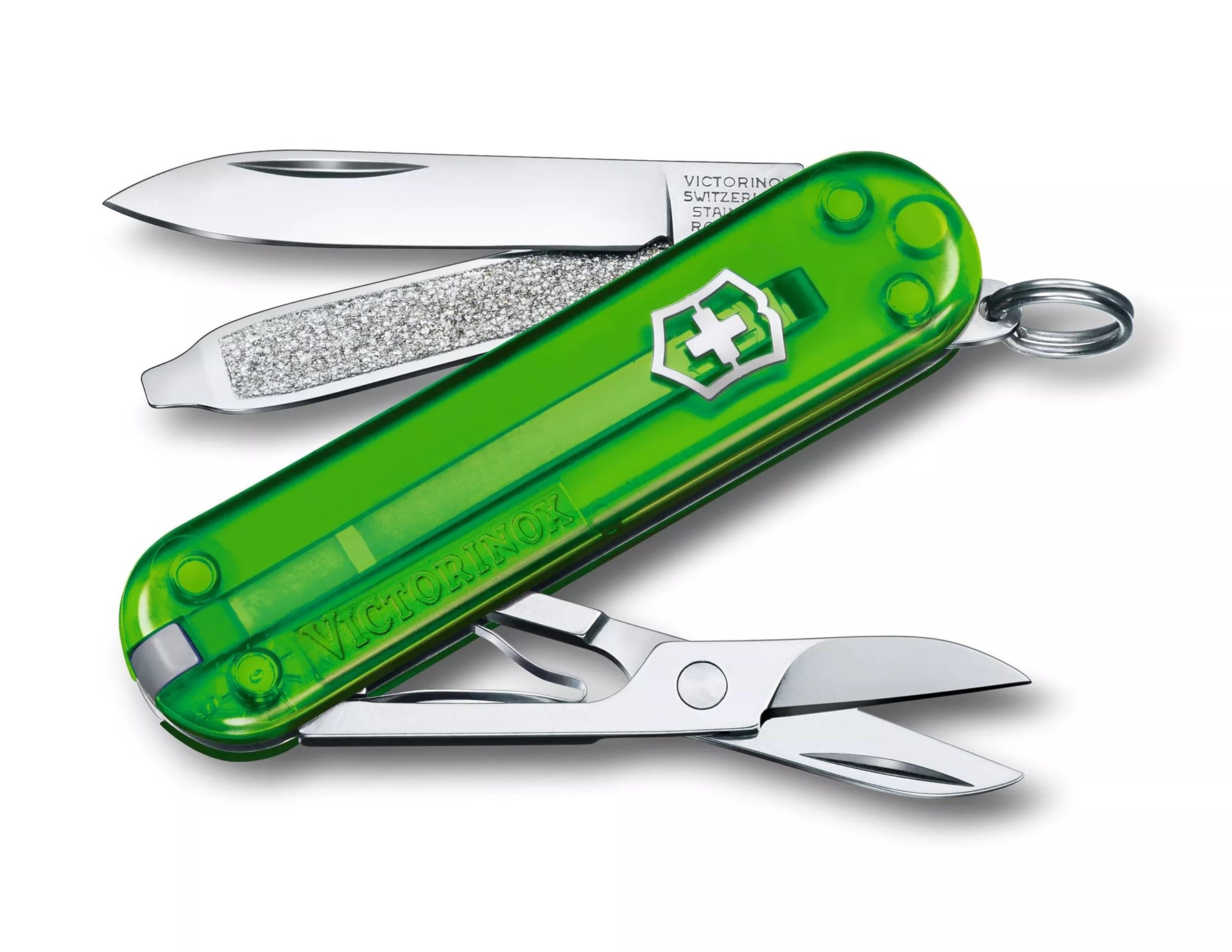 Şeffaf yeşil bir Victorinox çakı, görünen bir bıçak, kristallerle kaplı bir törpü ve makas ile beyaz bir arka plan üzerinde.