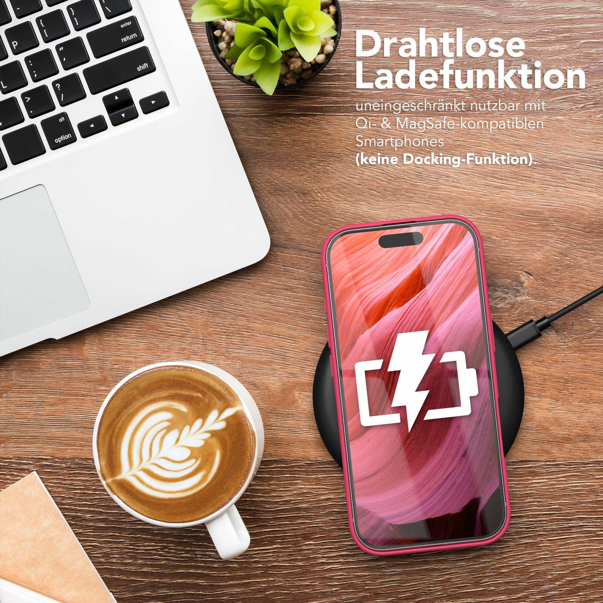 Ein Telefon lädt kabellos neben einer Laptoptastatur und einer Tasse Kaffee auf einem Holzschreibtisch.