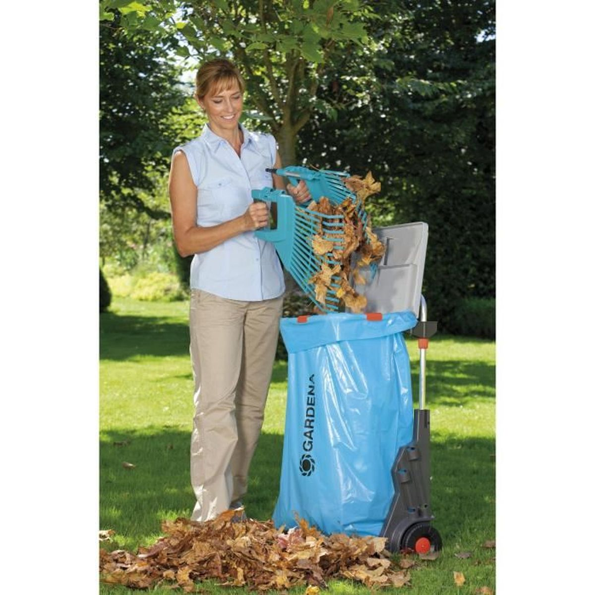 Eine Frau sammelt mit einem Rechen Laub in einen blauen Gardena-Sack.