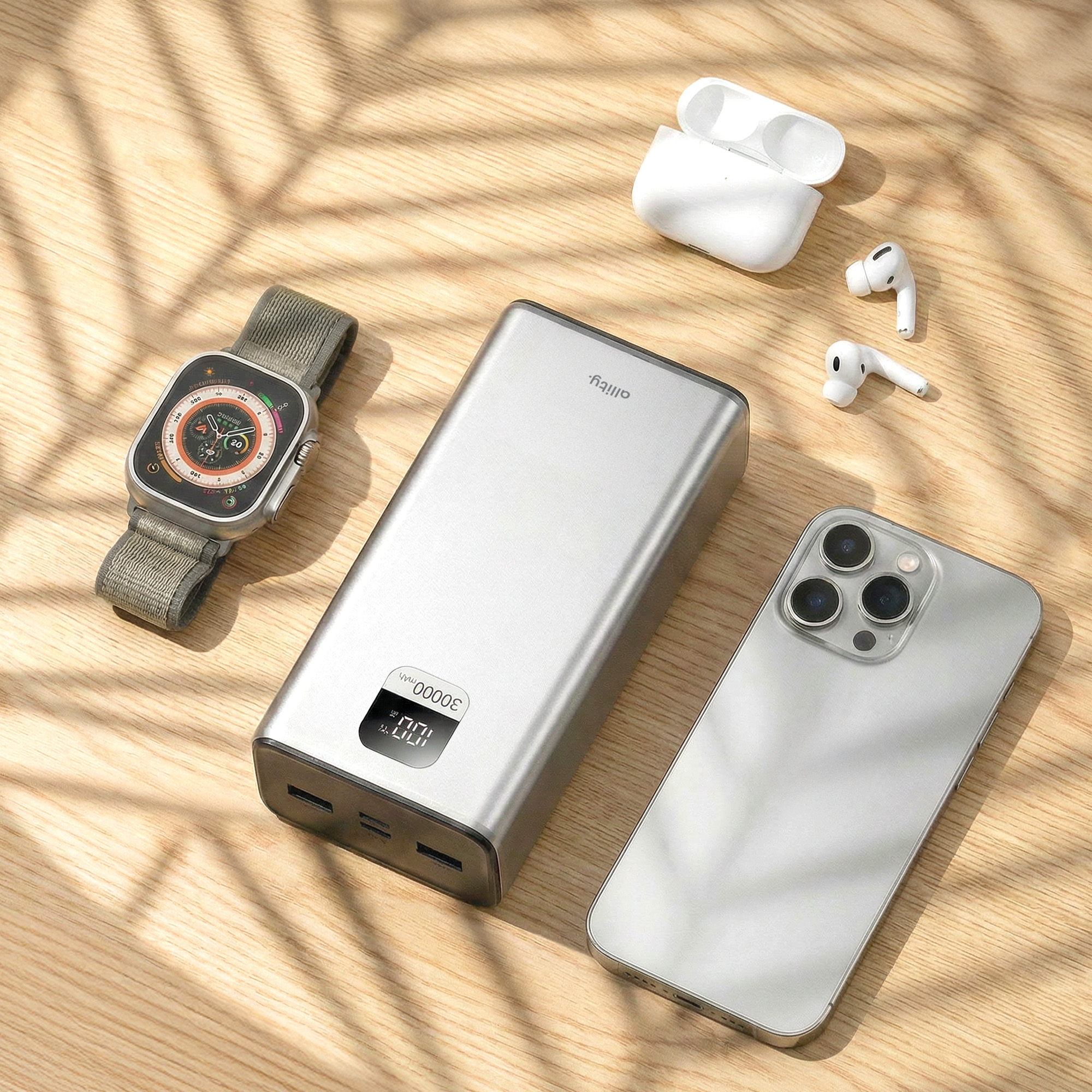 Eine silberne Powerbank, Smartwatch, weiße Ohrhörer und ein silbernes Smartphone sind ordentlich auf einer Holzoberfläche angeordnet.