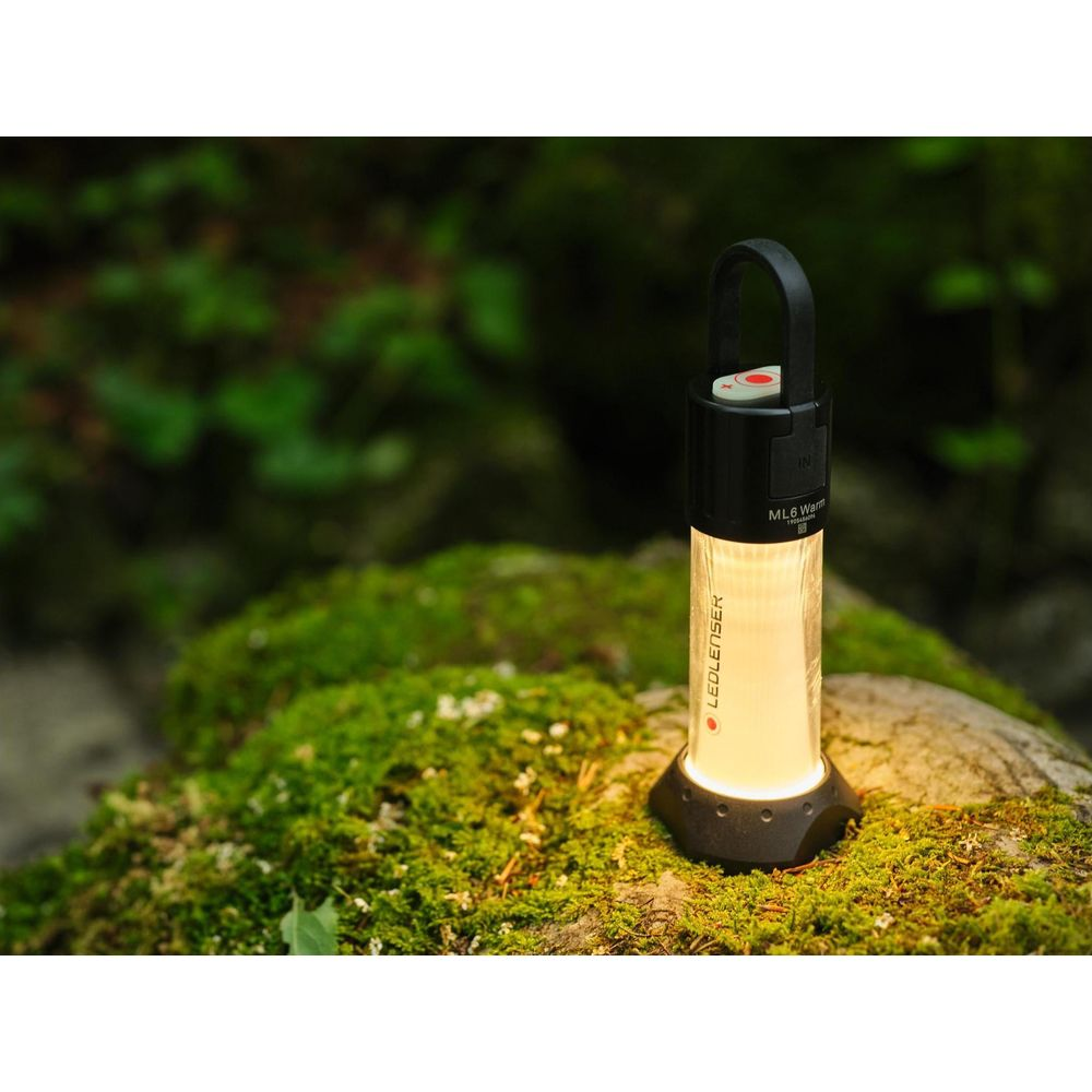 Eine Ledlenser ML6 Laterne sitzt auf moosigen Felsen in einem Wald.