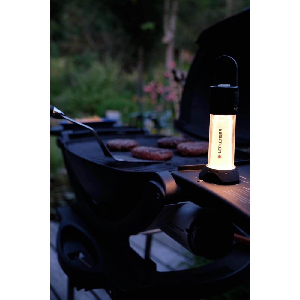 Burger auf einem Grill, beleuchtet von einer Laterne.
