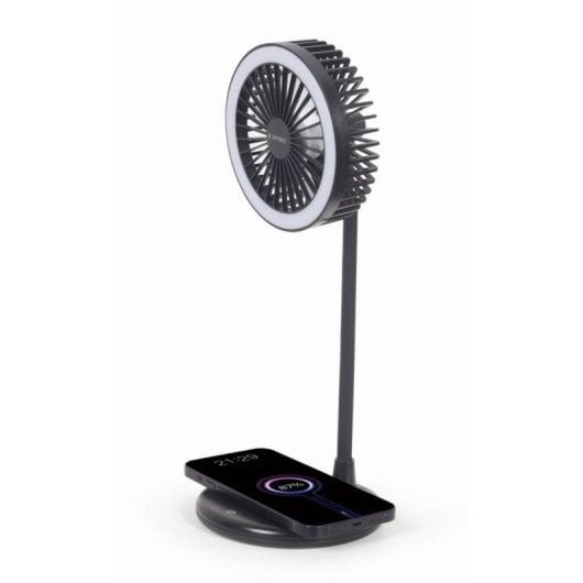Un ventilador negro con luz de anillo se alza sobre un teléfono cargando en una base.