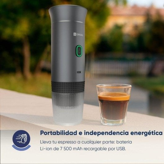 Una macchina da caffè espresso portatile grigia con un pulsante di accensione verde accanto a un bicchierino di caffè espresso su una superficie bianca all'aperto.