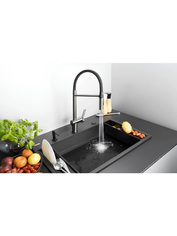 Su akıntılı siyah lavabo, yanında meyve ve çatal bıçak takımı.