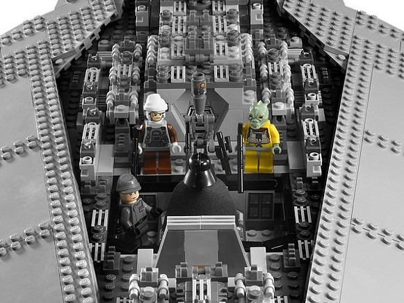 Drie Lego-figuren in de cockpit van een grijs ruimteschip met details.