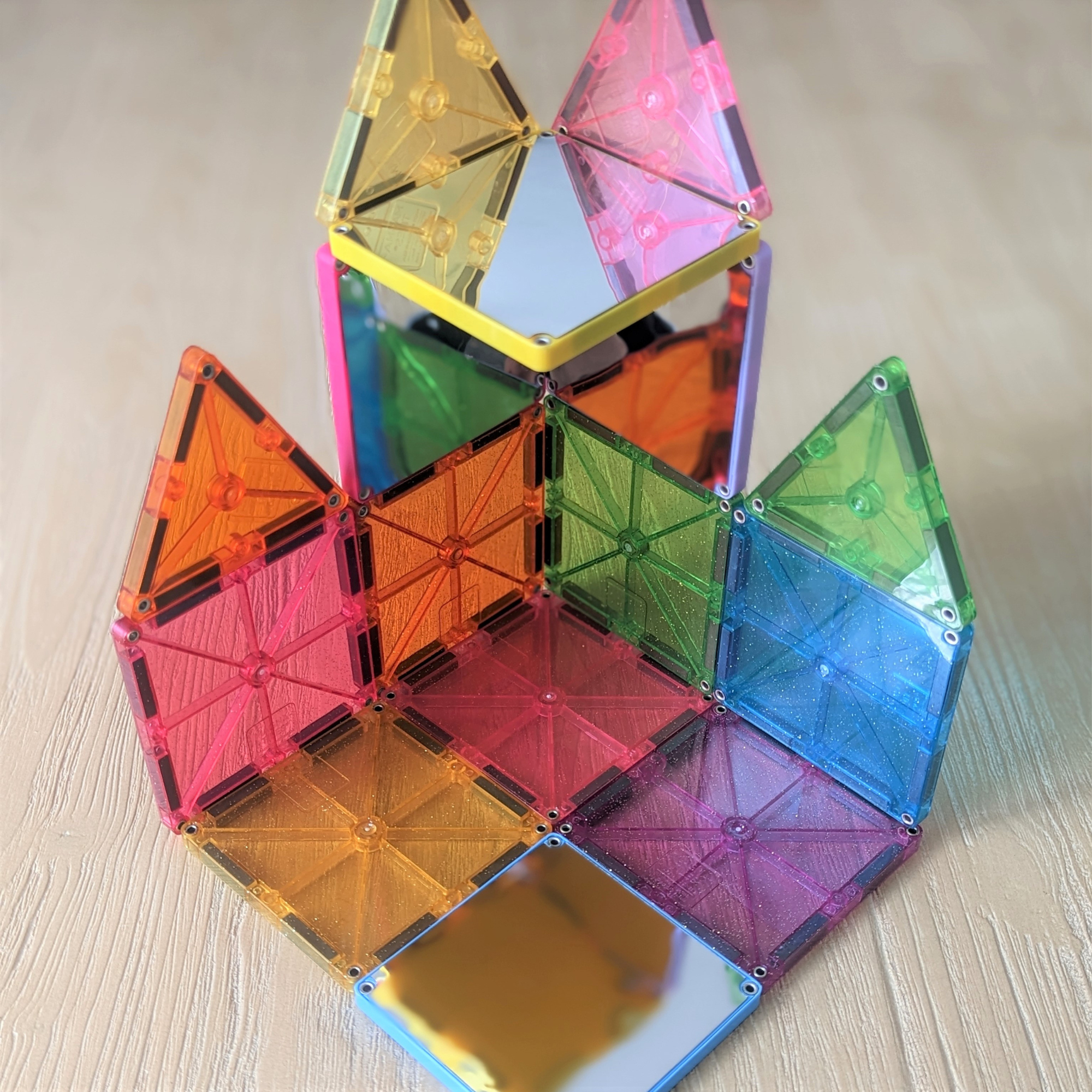 Transparente magnetische Bausteine in bunten Farben bilden eine komplexe Struktur auf einer Holzoberfläche.