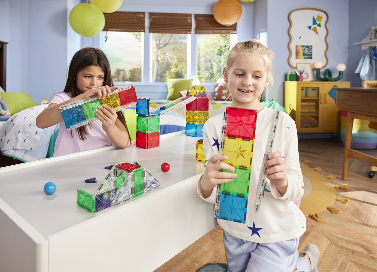 Deux filles construisent avec des blocs magnétiques colorés sur une table.