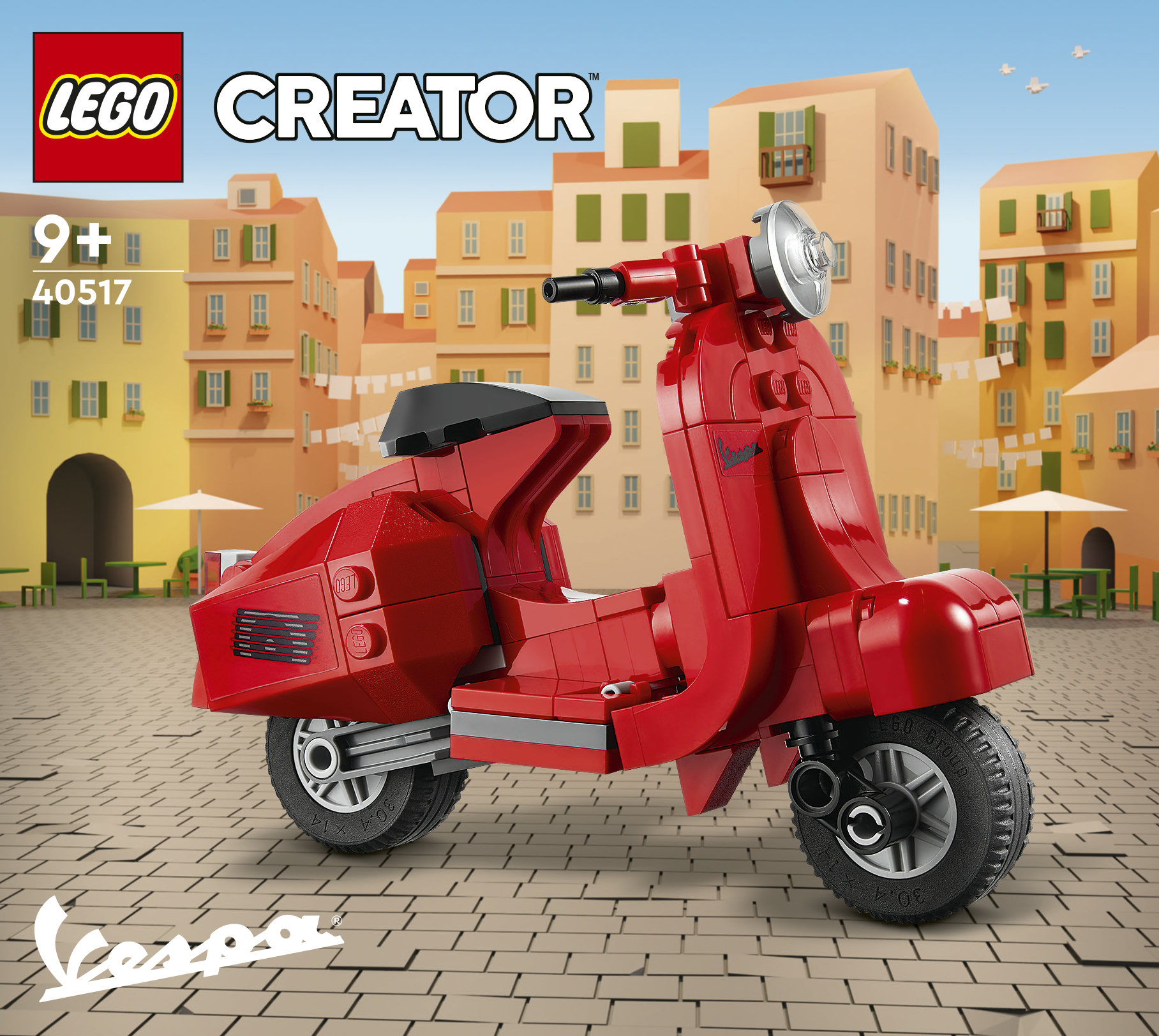 Kırmızı bir LEGO Vespa scooter, renkli binaların önündeki Arnavut kaldırımlı bir meydanda duruyor.