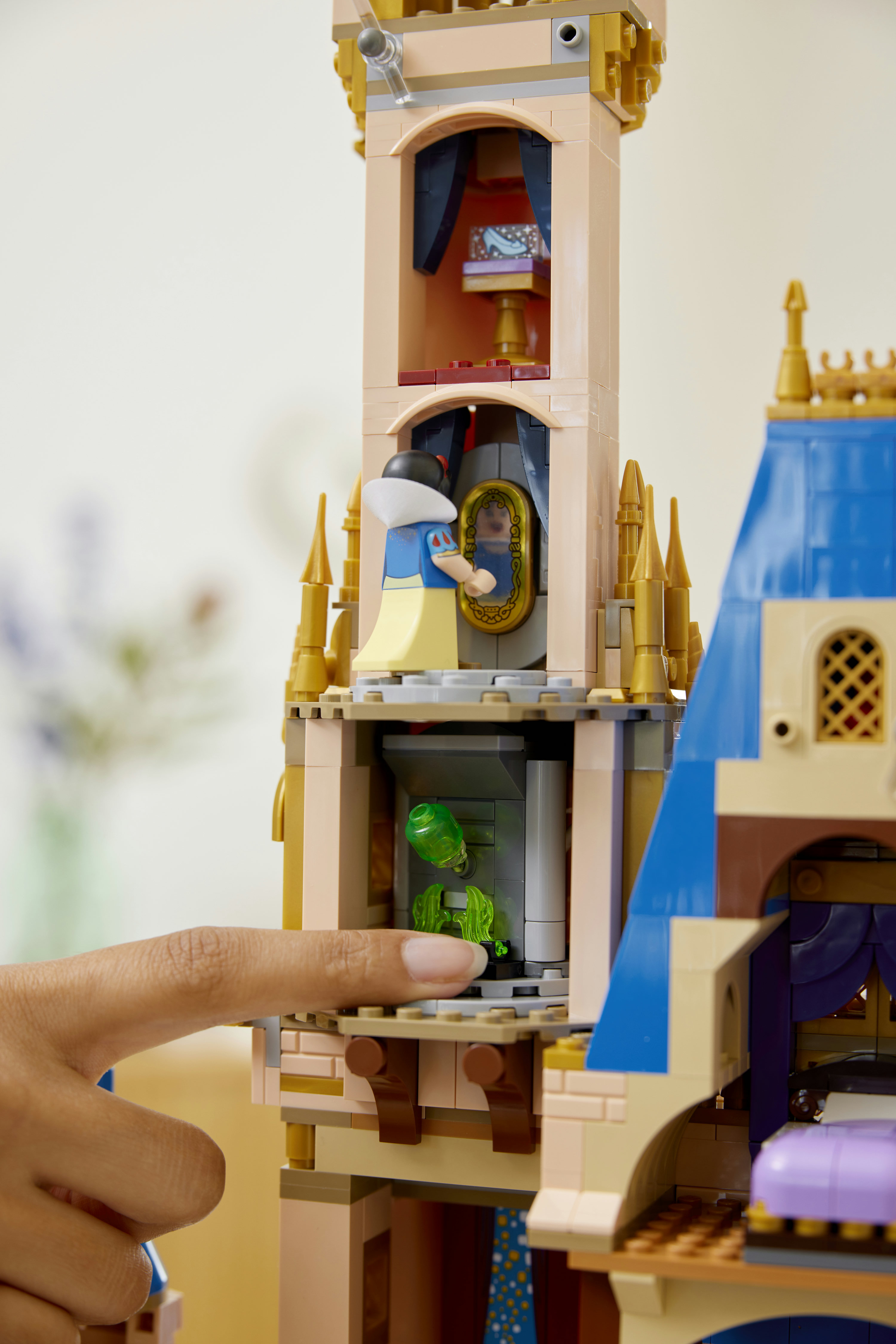 Una mano interagisce con un castello Lego, con Biancaneve che si guarda in uno specchio e una pozione verde in una camera inferiore.