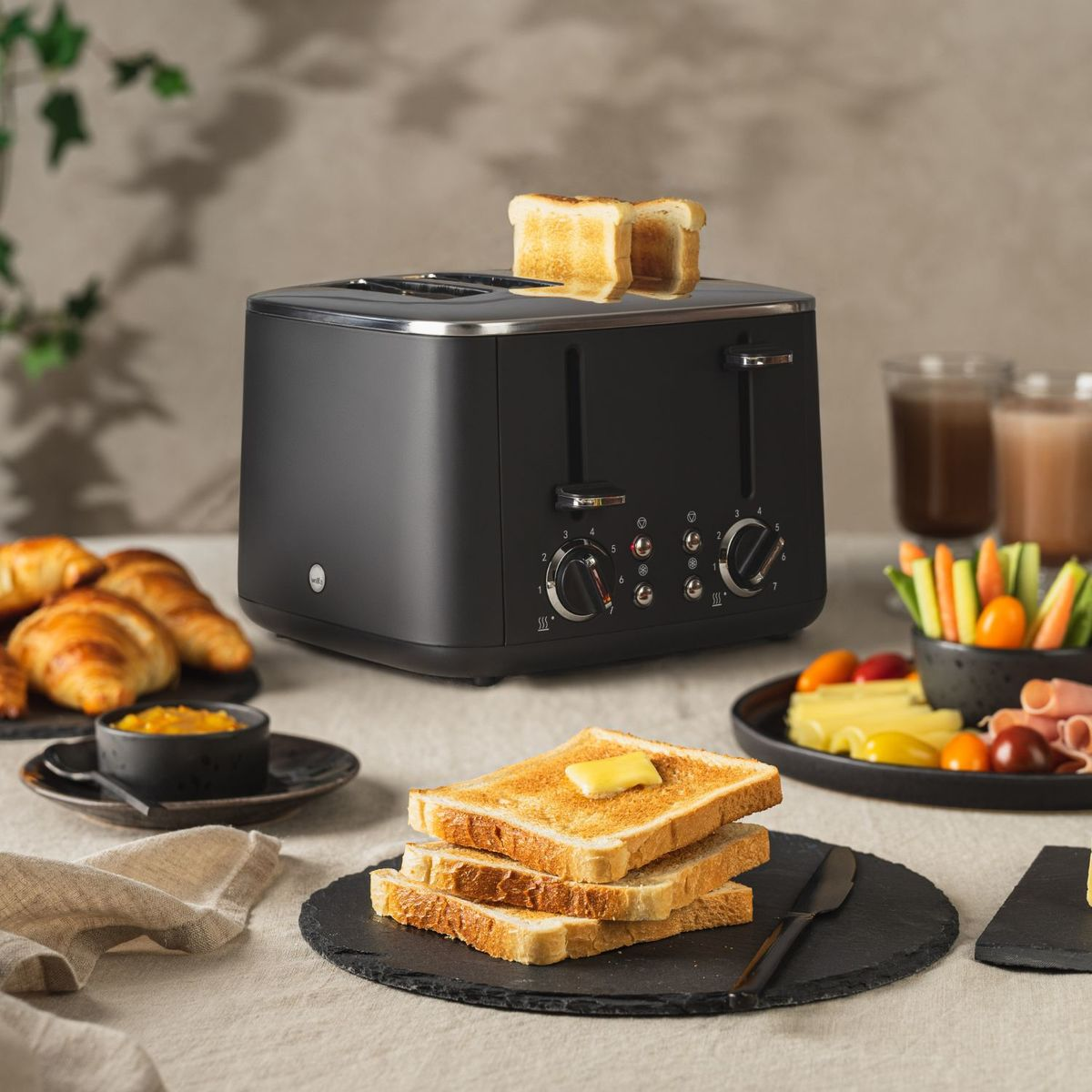Tostapane nero con toast, croissant, marmellata e bastoncini di verdure.