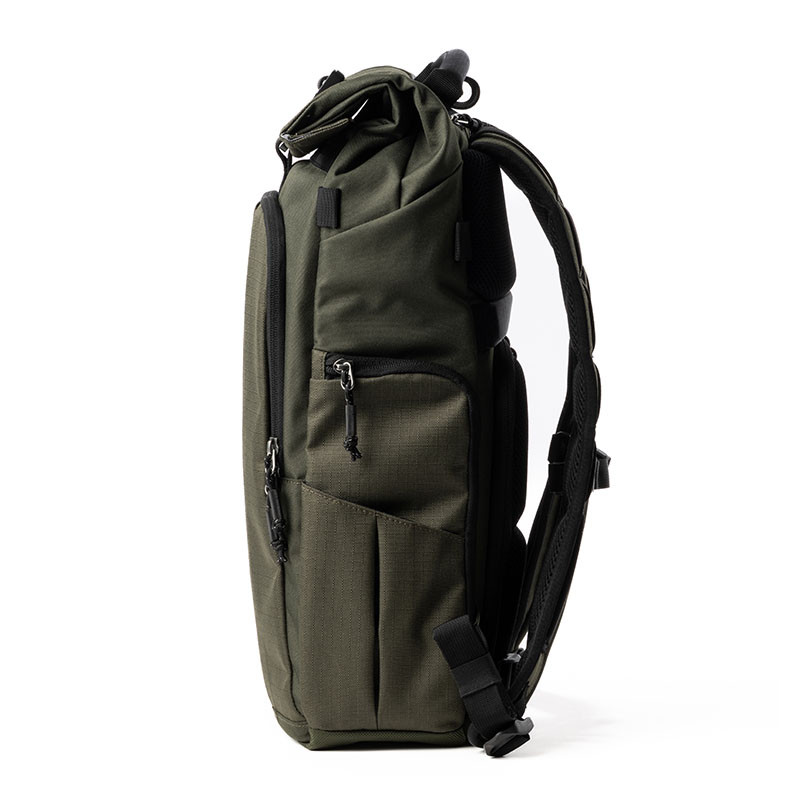 A green backpack with black straps and zippers is shown from the side against a white background.