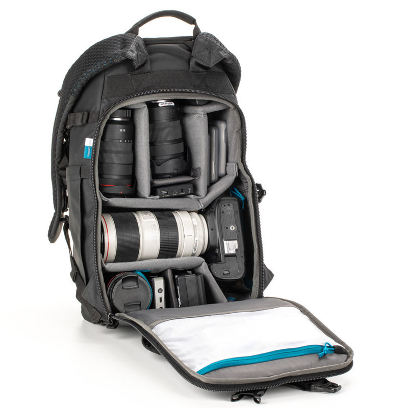 An open backpack with cameras and lenses, on a white background.