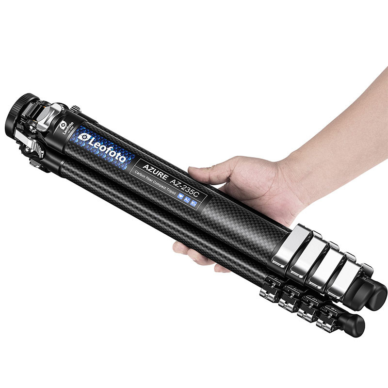 Eine Hand hält ein schwarzes Carbonfaser-Stativ der Marke Leofoto Azure AZ-235C.