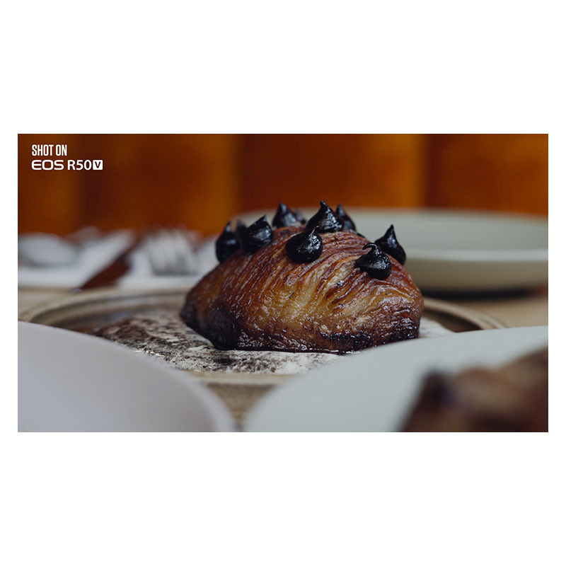 Un pasticcino dorato con guarnizione scura su un piatto, spolverato di zucchero a velo.