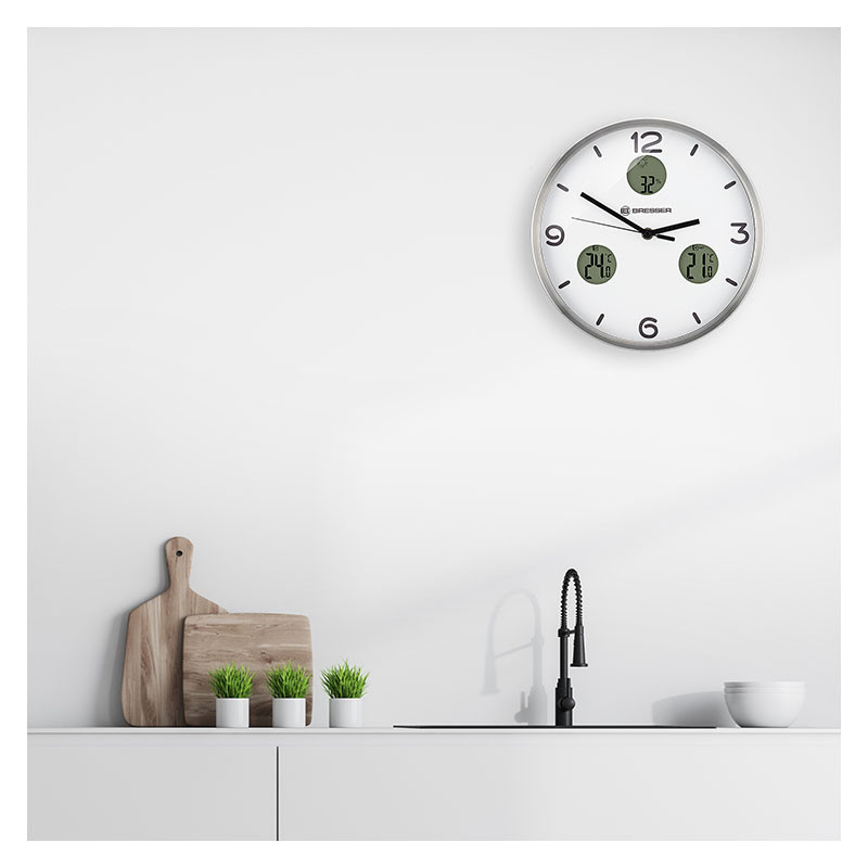 Un área de fregadero de cocina moderna con reloj, tablas de cortar y plantas.