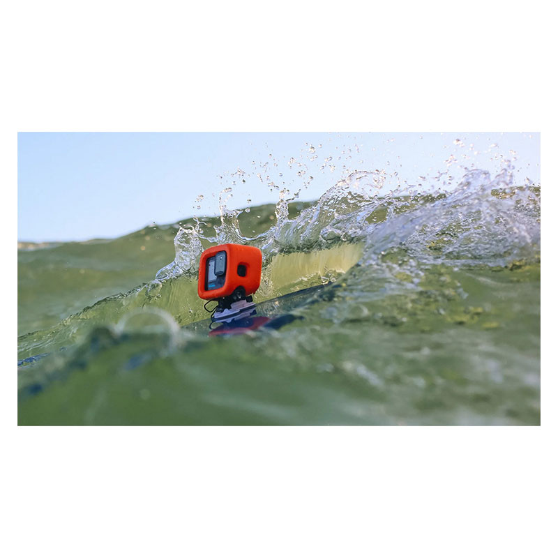 Orange GoPro in einem orangefarbenen Gehäuse auf einem Surfbrett, das von einer Welle umspült wird.