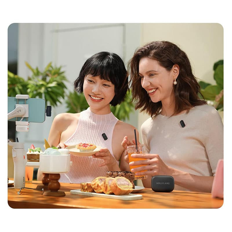 Zwei Frauen lachen bei einem Essen im Freien mit Snacks und Getränken.