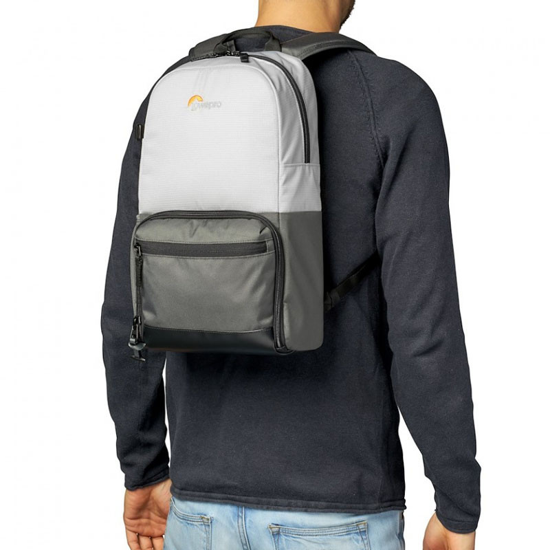 Un homme porte un sac à dos bicolore, gris et blanc, avec un logo Lowepro.