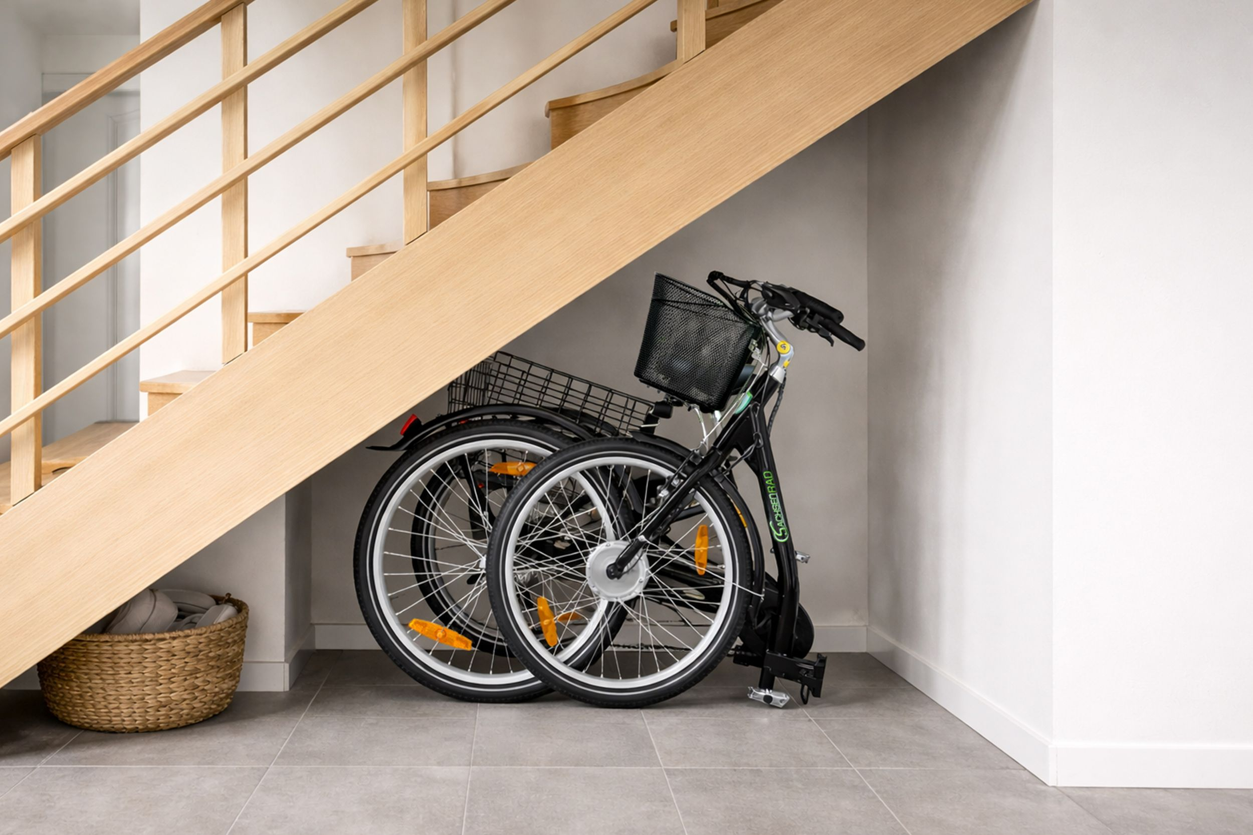 Ein schwarzes Fahrrad mit Korb steht unter einer Holztreppe neben einem Weidenkorb.