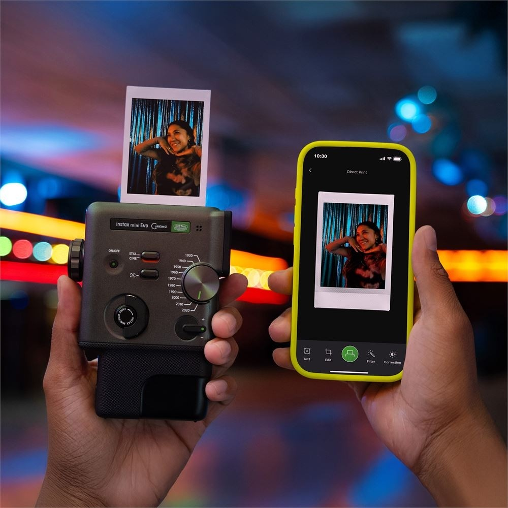 Eller, aynı fotoğrafı gösteren bir telefonun yanında fotoğraf basan Instax Mini Evo kamerayı tutuyor.