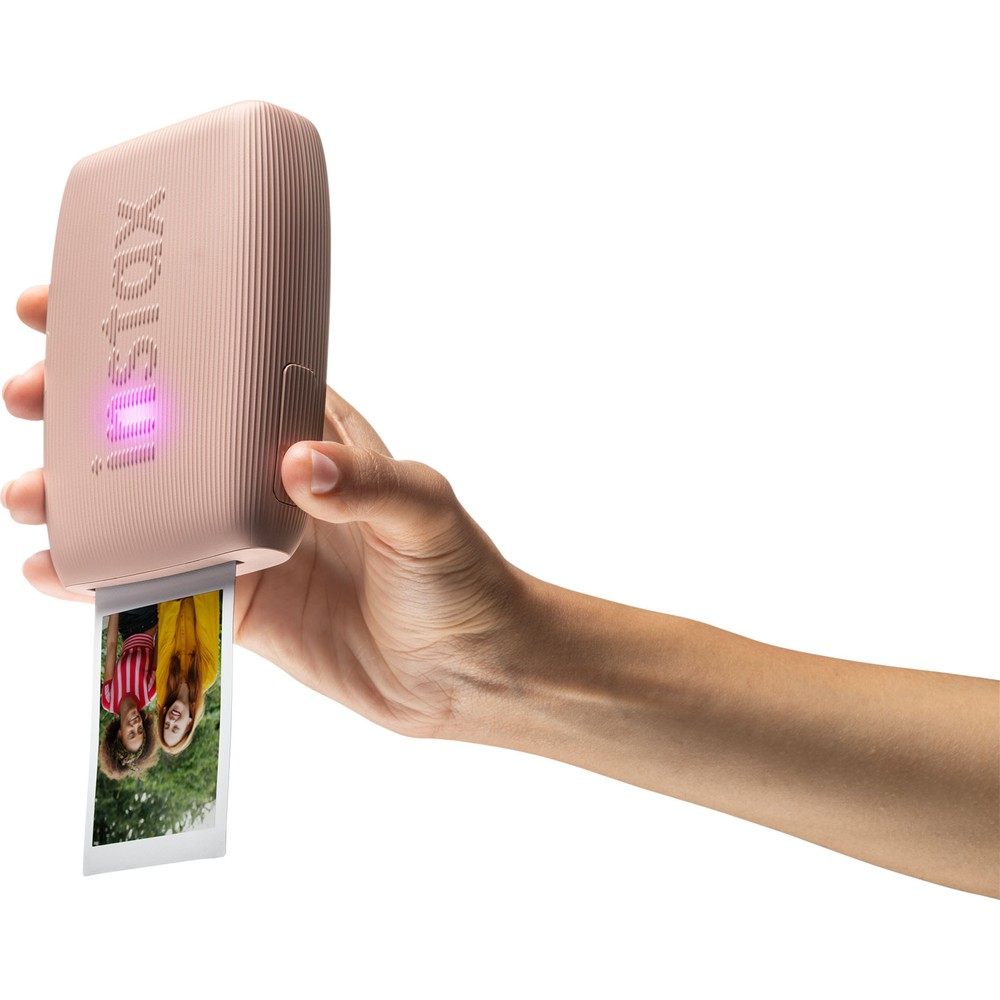 Bir el, iki kızın fotoğrafını basan pembe bir Instax yazıcı tutuyor.