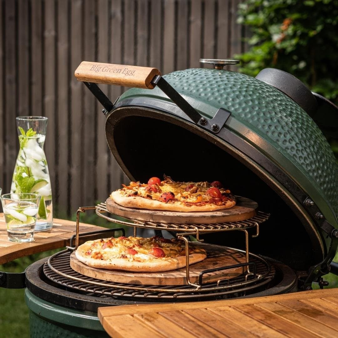 Yeşil bir ızgarada raflarda pişen iki pizza. Yanında nane ve su dolu sürahi duruyor.