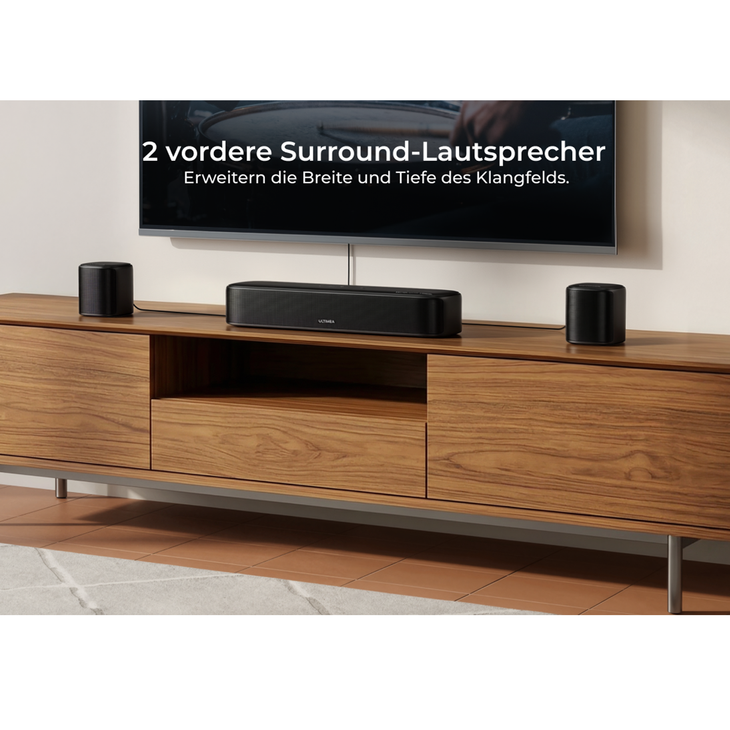 Zwei schwarze Lautsprecher und eine Soundbar stehen auf einem Holzmöbel vor einem Fernseher.