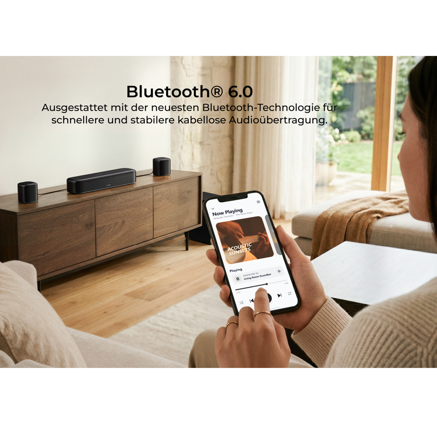 Schwarzer Bluetooth-Lautsprecher mit zwei kleineren Lautsprechern auf einem Holzschrank.