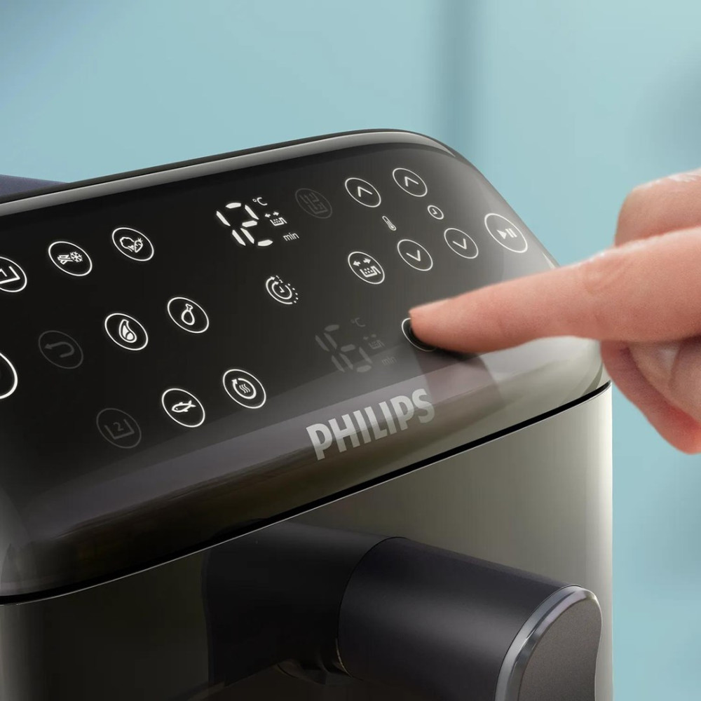 Ein Finger drückt auf das Bedienfeld eines schwarzen Philips Airfryers.