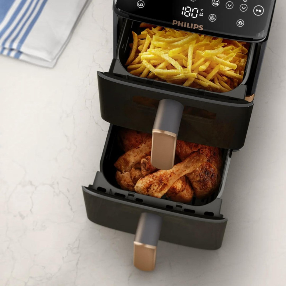 Ein schwarzer Philips-Heißluftfritteuse mit Pommes und Hähnchenteilen.