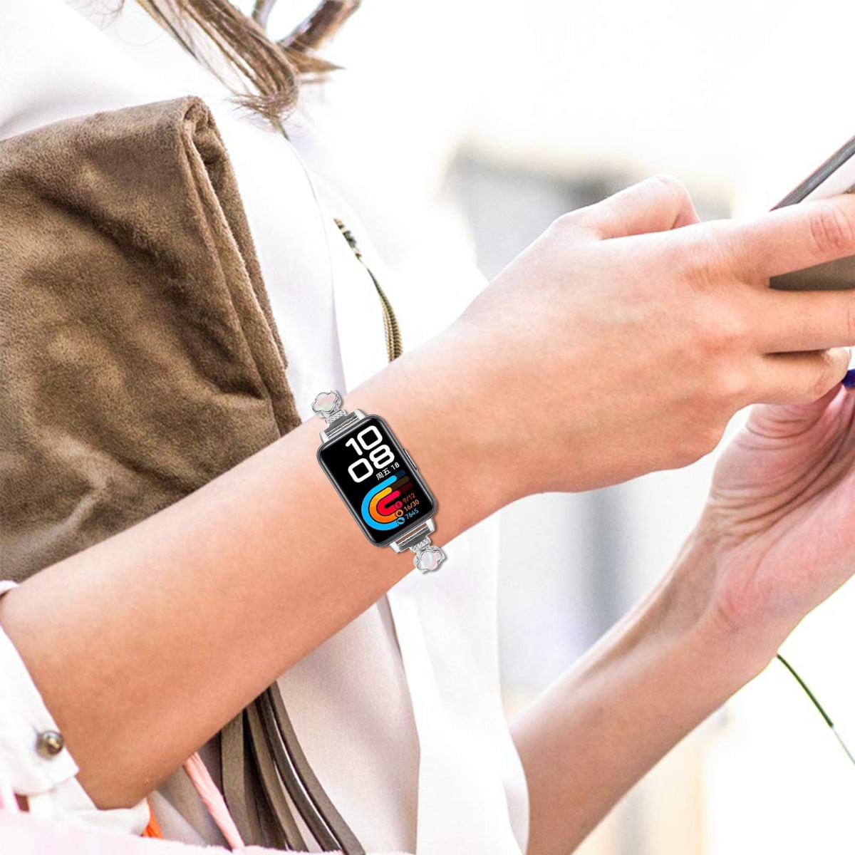 Eine Person trägt eine Smartwatch mit buntem Zifferblatt und hält ein Smartphone in der Hand.