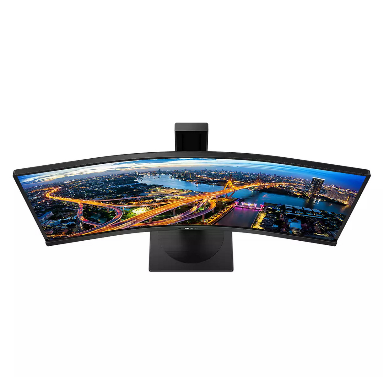 Un monitor curvo muestra un paisaje urbano nocturno con autopistas y edificios iluminados.
