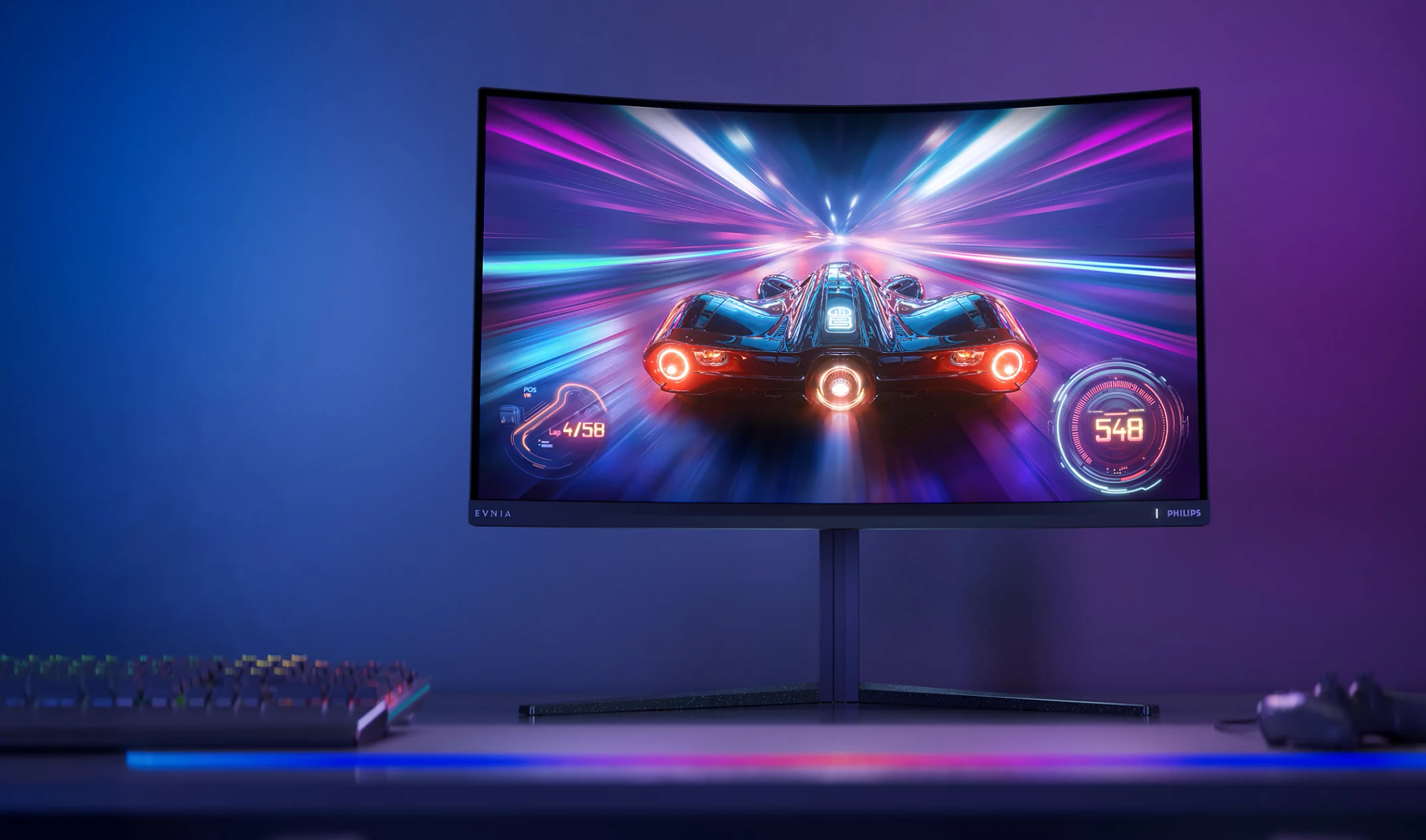 Monitor curvo mostra auto da corsa futuristica su pista al neon. Tastiera RGB vicina.