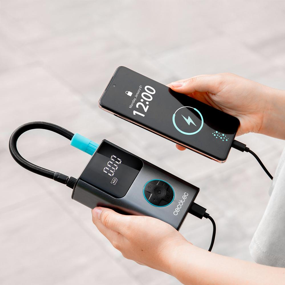 Un smartphone está siendo cargado por un compresor de aire portátil que también es un inflador de neumáticos.