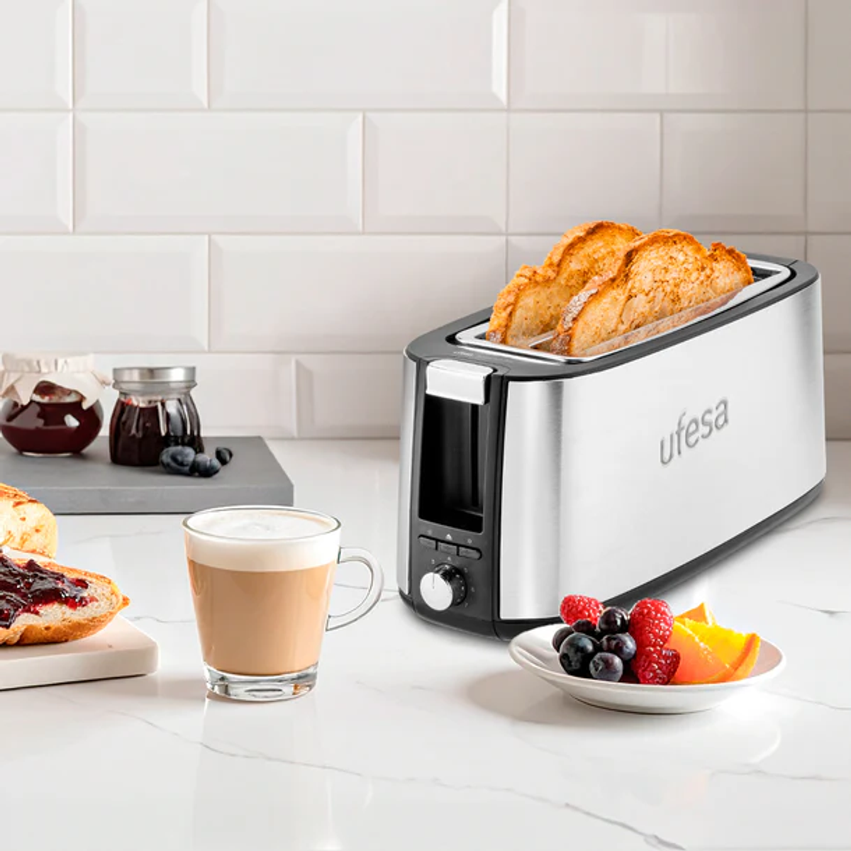 Un tostapane con toast, caffè, marmellata e frutta su un bancone da cucina.