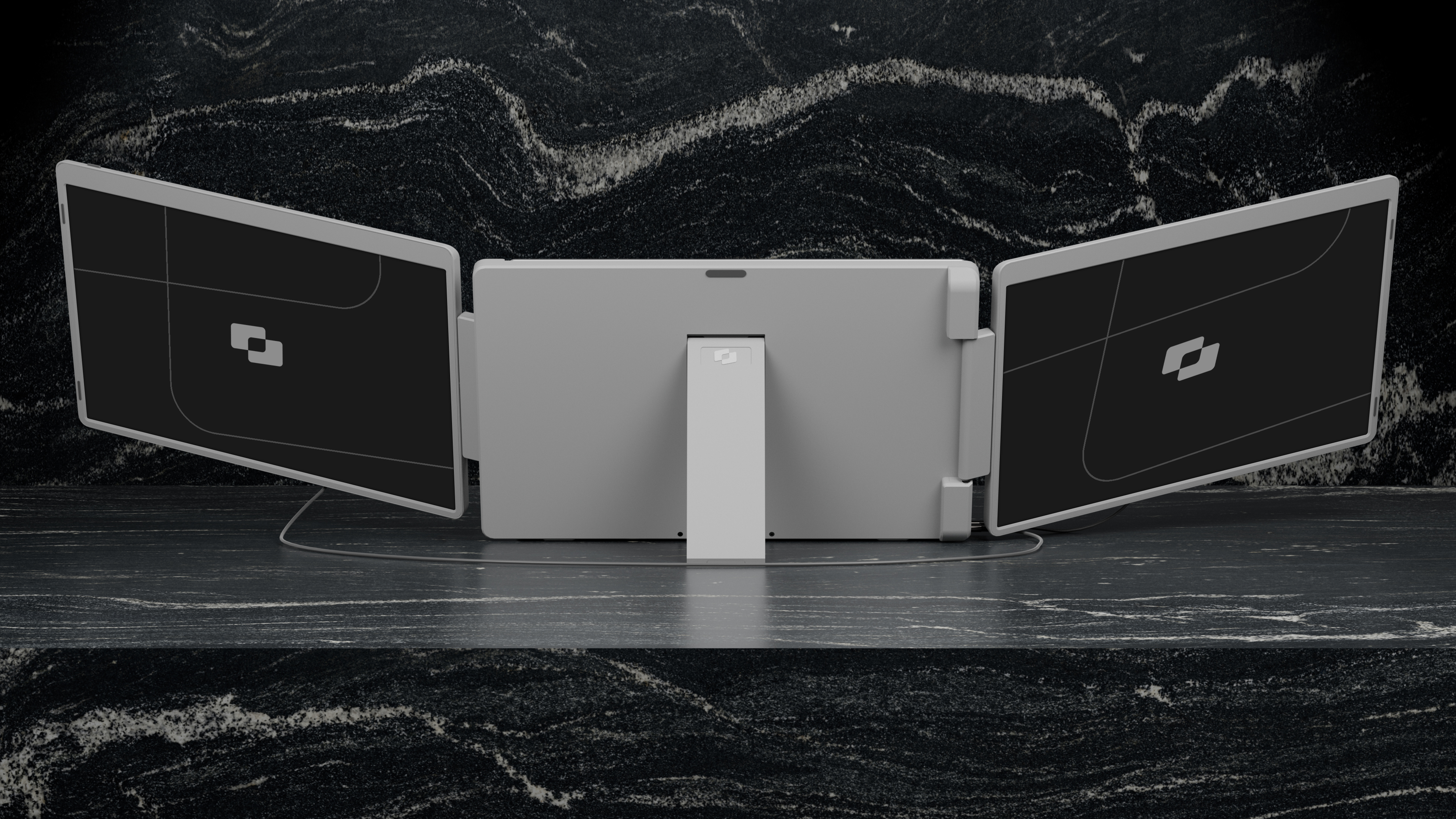 Een grijze triple monitor setup op een zwart granieten oppervlak, schermen tonen logo's.