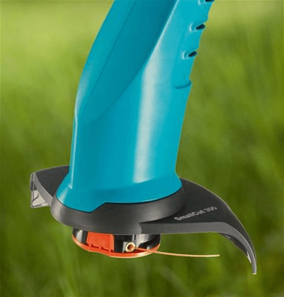 Ein blauer Trimmerkopf mit orangefarbener Spule und Nylonfaden vor grünem Gras.